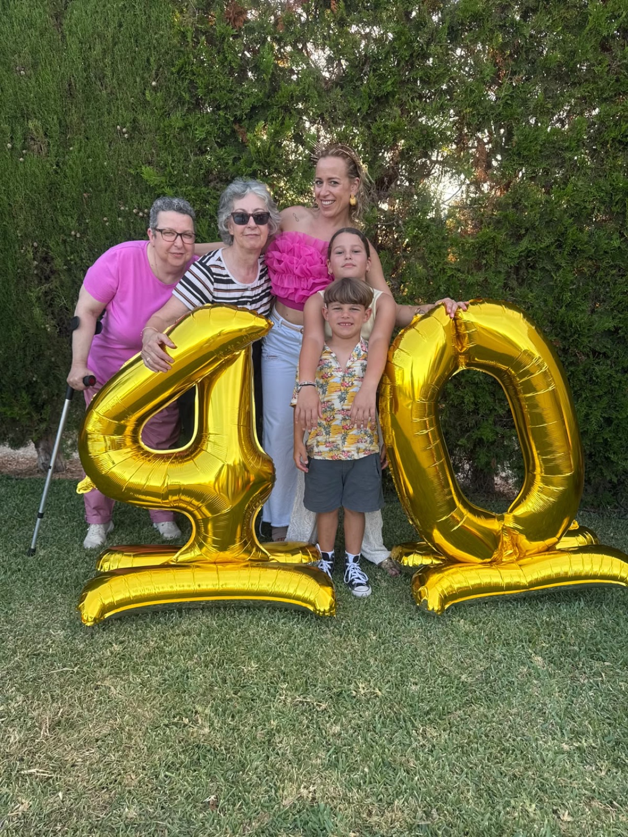 Elena con su familia junto a globos dorados de 40.