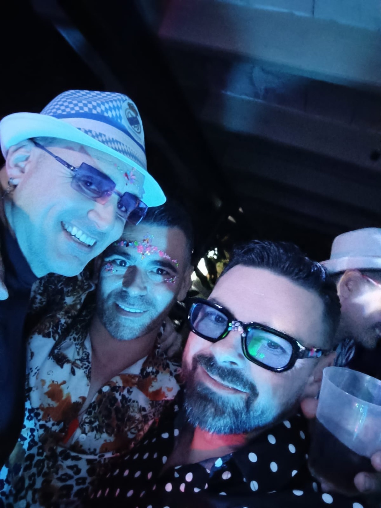 Amigos posando con gafas y luz azul en la fiesta.